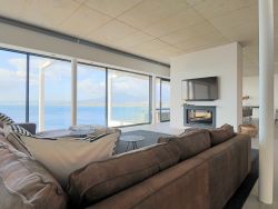 The open plan lounge with sea view, seven seat sofa, 60 inch TV and sound bar, double sided wood burning fire place and electric roller blinds