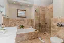 Deluxe Self-Catering en suite bathroom with bath, double vanity basins, double headed shower, toilet and bathroom wall heater