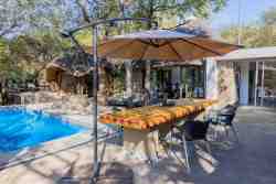 Sky Villa - The outside dining area with a scenic view of the pool and bush. At Sky Villa, it's all about outdoor living!
