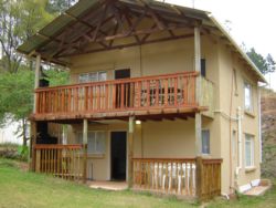 Please take note that both levels of the self-catering guest house are open plan (no separate rooms). On the bottom Level:  Veranda with a built-in-braai. It has a full kitchen, bathroom with a shower, double bed, two single beds and dining table.  Upper Level:  Lounge, double bed, two 3/4 beds, bathroom with two showers and a wooden deck on top.  