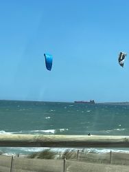 Enjoying afternoon walk on promonade with kitesurfers