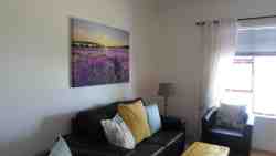 Comfortable open-plan lounge and kitchen has a flat-screen TV and view of the front garden.