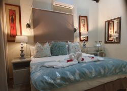 Main bedroom with king size bed. Bathroom with bath, basin, toilet.  Airconditioner and ceiling fan.  Door leading onto patio.