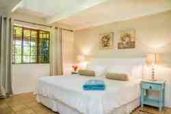 Main bedroom with queen bed, dressing table, cupboard and garden view.