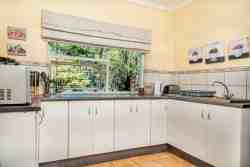 Separate kitchen with microwave, two plate stove, fridge and freezer, sink, kettle, crockery and cutlery.