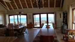 Open plan dining area facing towards first floor deck with semi-enclosed BBQ corner, overlooking ocean