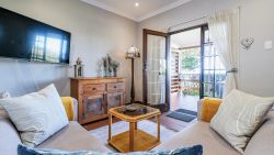 Lounge with l-shaped couch and large flatscreen TV and sea views