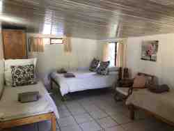 Chalet Sleeps 6: Bedroom with a double bed and two single beds, open plan kitchen and lounge with a double bed and a bathroom with a shower and another bathroom with a bath. Patio and braai